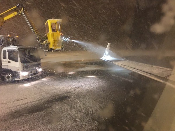 翼に積もった雪の除雪作業